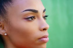 Side portrait of Black female in front of green background