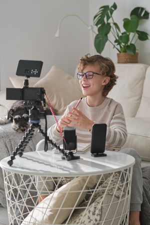 Boy laughing while recording video for blog at home