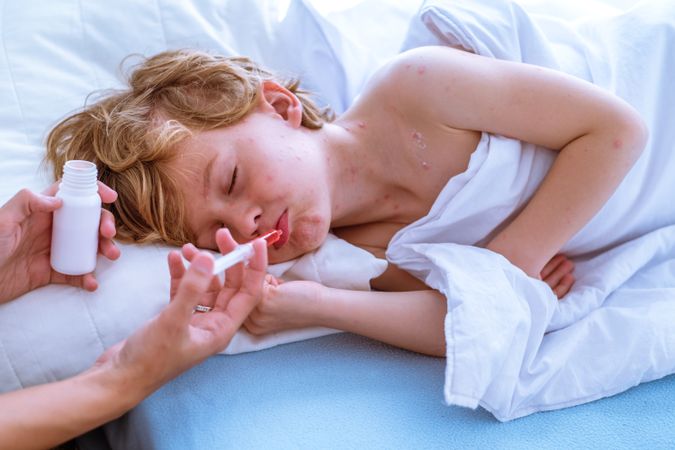 Upset son taking medicine from mom
