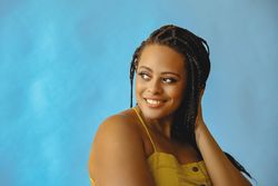 Portrait of smiling female with long braided hair looking away in yellow shirt, copy space