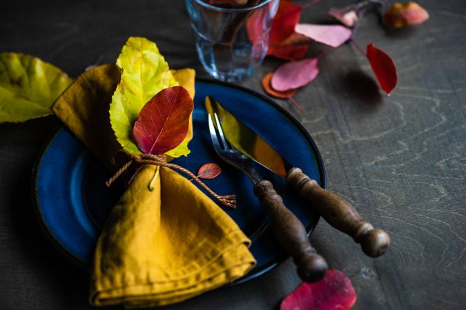 Autumnal place setting with yellow napkin & colorful leaves on navy plate