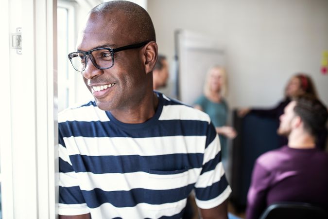 Smiling Black man looking out of the window in an office
