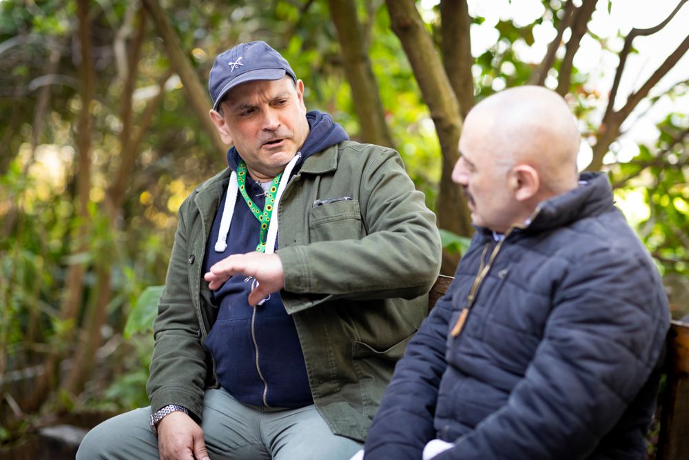 Two male friends talking outside on a park bench
