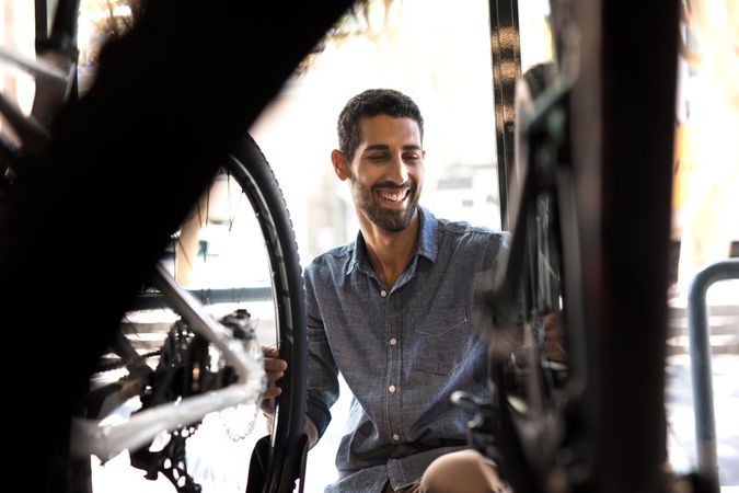 Smiling man in workshop looking at bicycles