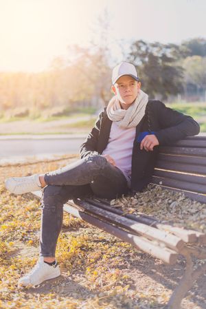 Teenager sitting on a wooden bench in a city park