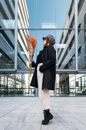 Stylish female holding flowers on street