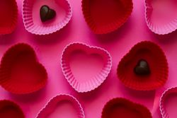 Heart shaped chocolates on a pink background with red and pink hearts.