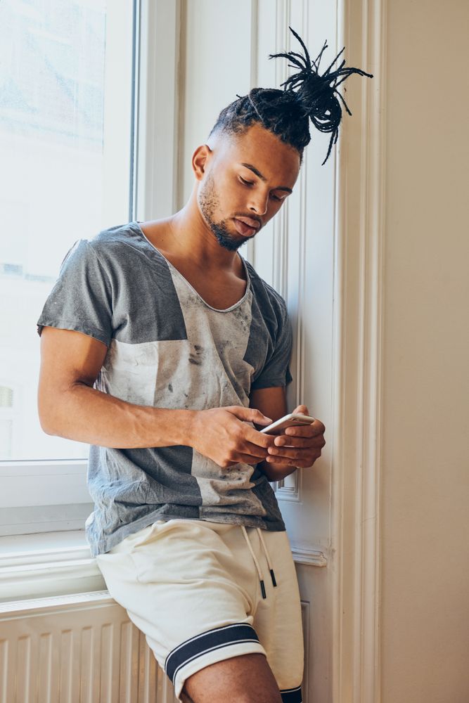 Black braided male using smartphone