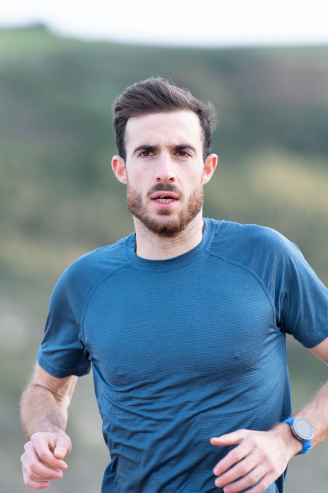 Sportsman in active wear jogging on lonely beach