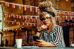 Black woman in stripe shirt on video call in cafe