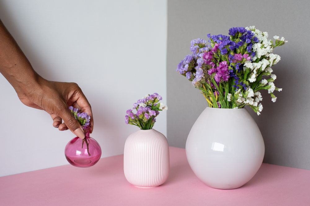 Hand fixing a vase of sea lavender flowers