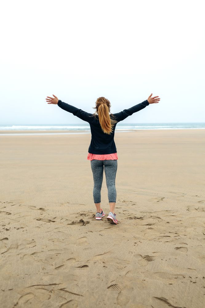 Young woman watching the sea with hands up