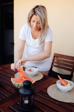 Pregnant woman cutting watermelon to bowl