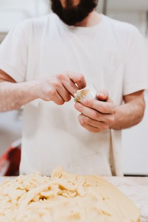 Unrecognizable cook putting pastry dough in cup
