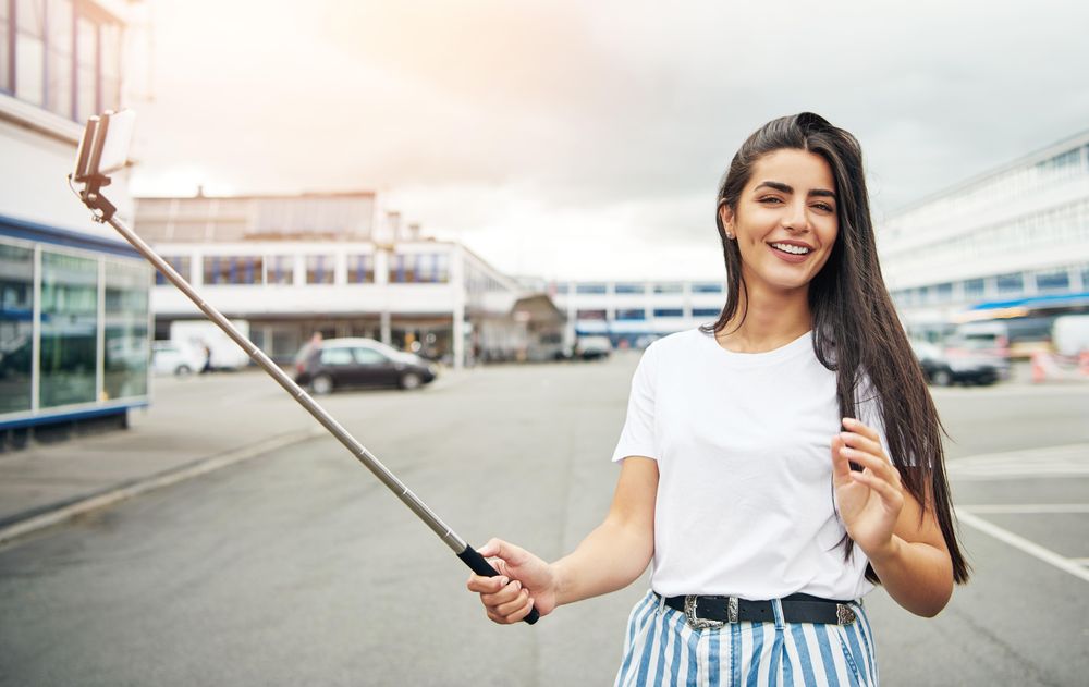 Tanned woman with selfie stick on overcast day