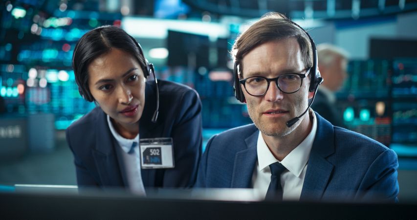 Two Successful Stock Exchange Traders Using Computer, Discussing Commodities Investments for an International Business Partner, Working in a Monitoring Center with Multiple Computer Screens