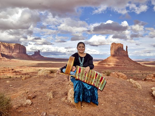 Najavo woman smiling with baby against Monument Valley mesas