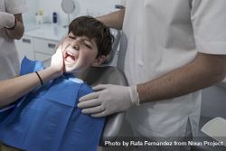 Teenage boy with tooth pain sitting in dental chair 0PxWN0