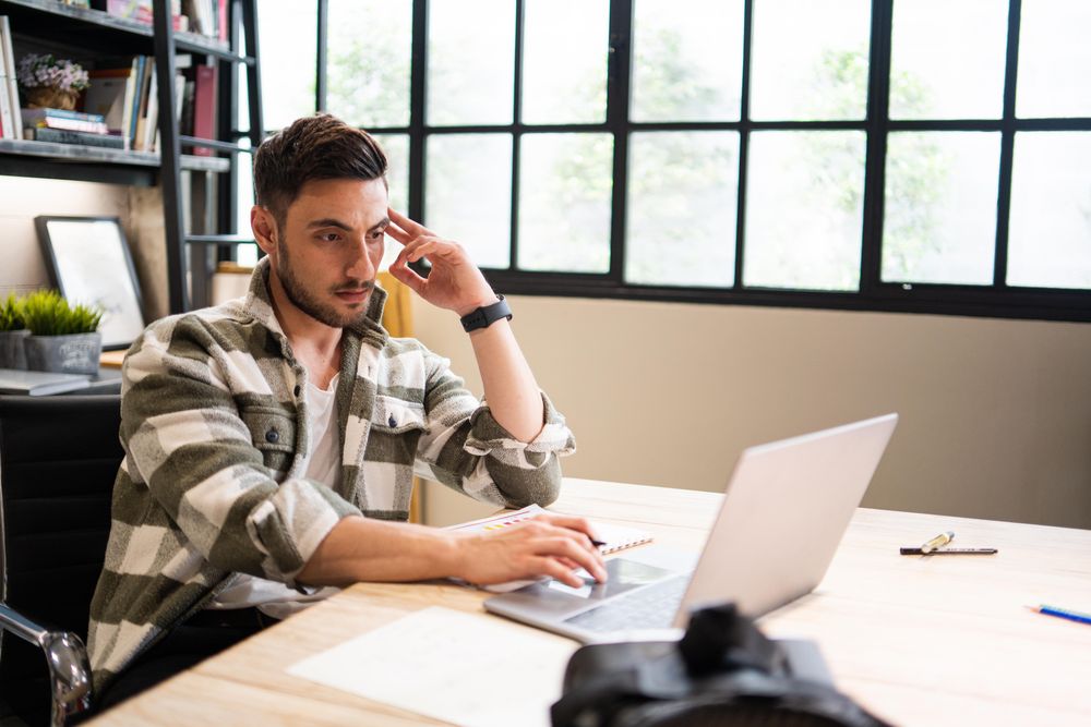 Serious young professional at work at a laptop in relaxed modern office