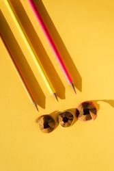 Three colored pencils and shavings, on yellow background