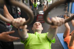 A male trainee hanging from the rings at the gym