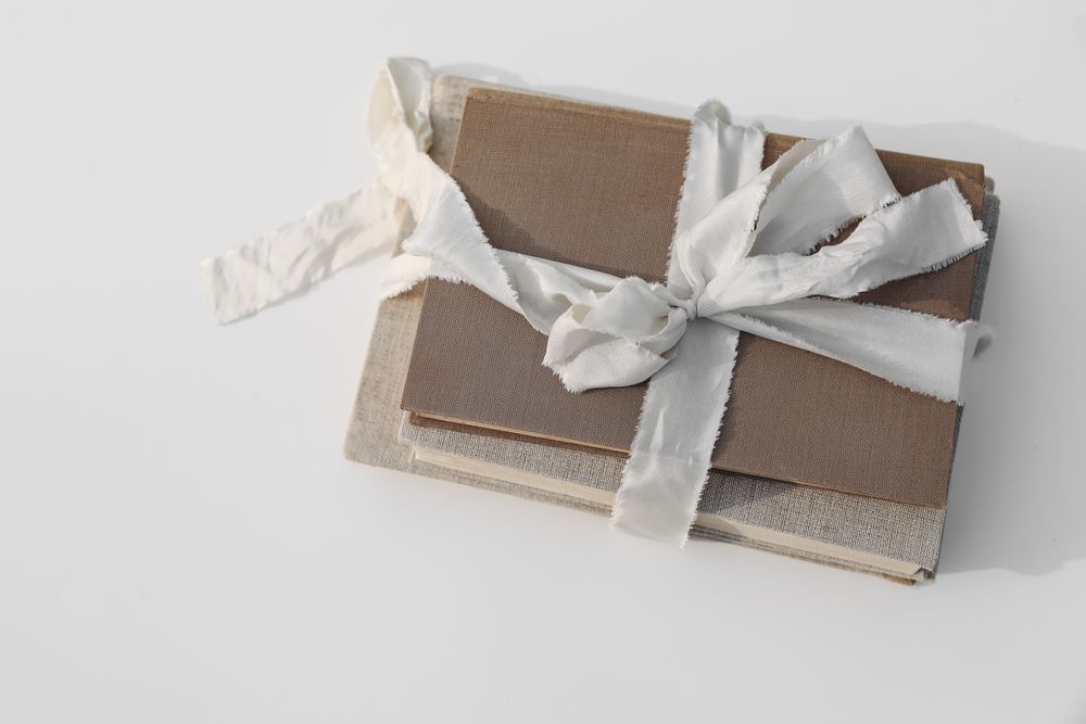 Stack of three old, vintage books tied up with beige ribbon with linen hard cover