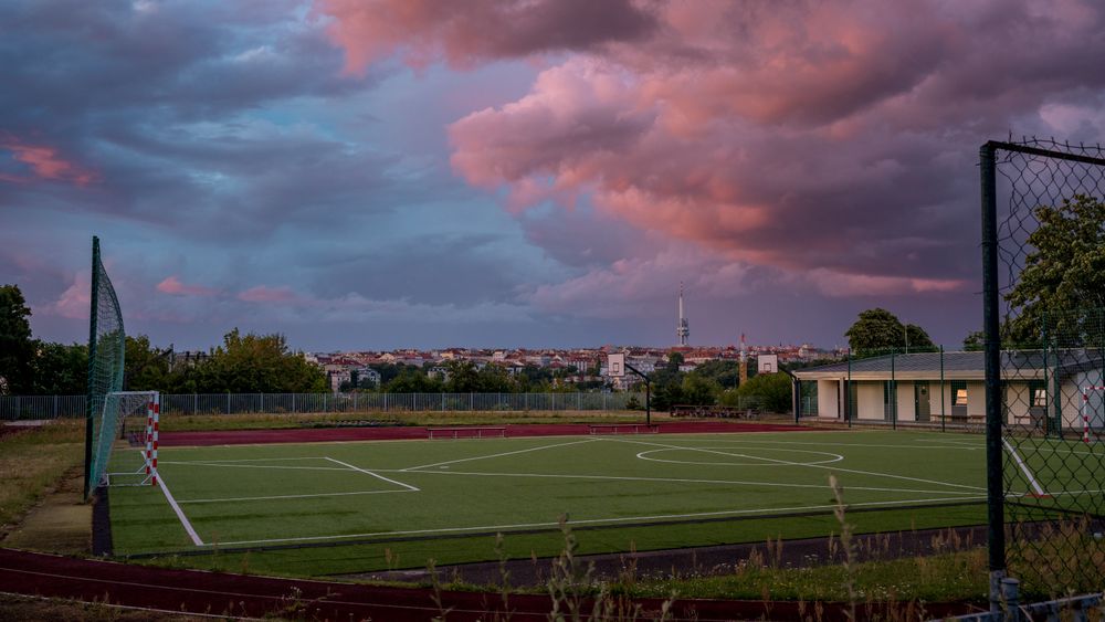 Sports field with beautiful pink clouds with Prague panorama