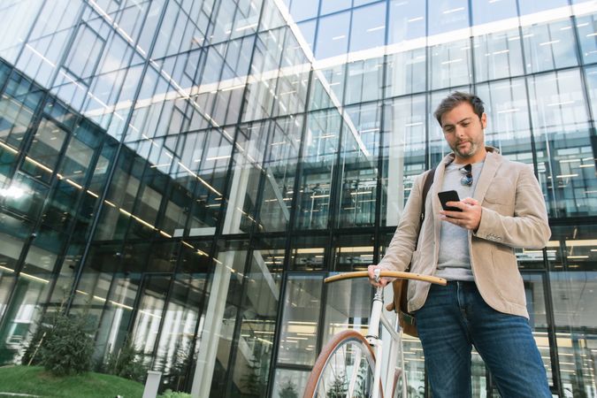 Man phoning while standing against modern building in downtown
