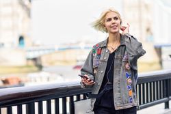 Blonde woman smiling and listening to music on phone along river walk