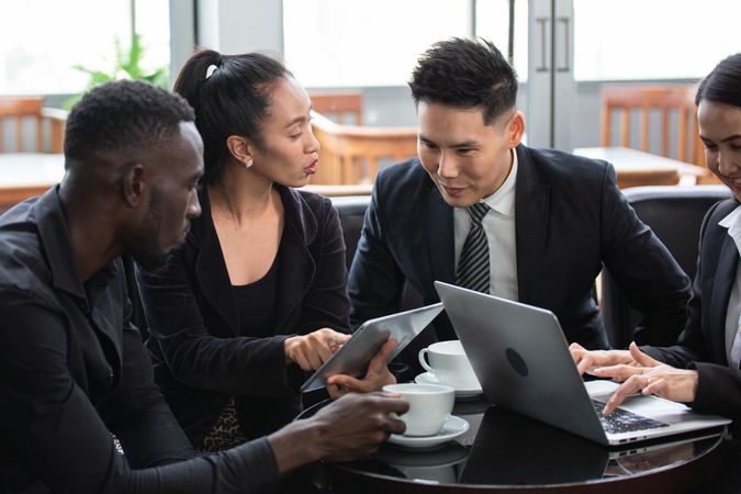 Diverse group of business people having a meeting in coffee shop with laptop and tablet