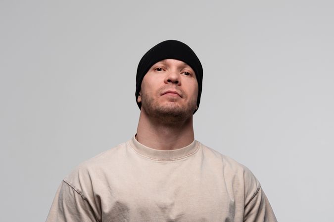 Man in beanie and beige t-shirt, serious expression