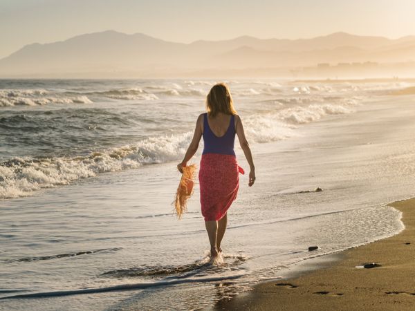 Woman holding walking along seaside