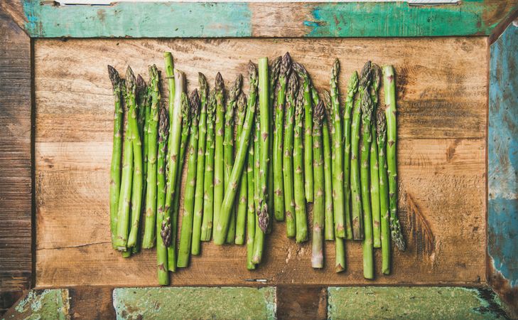 Asparagus lined up on wooden board with green trim