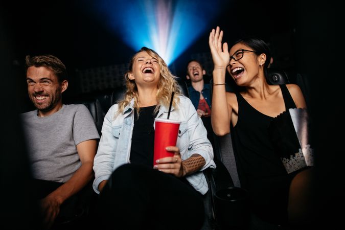 Young women and men watching comedy movie in cinema