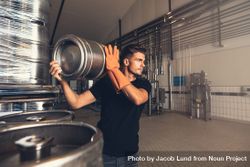 Business owner lifting metal barrel in brewery factory 0JzEl0