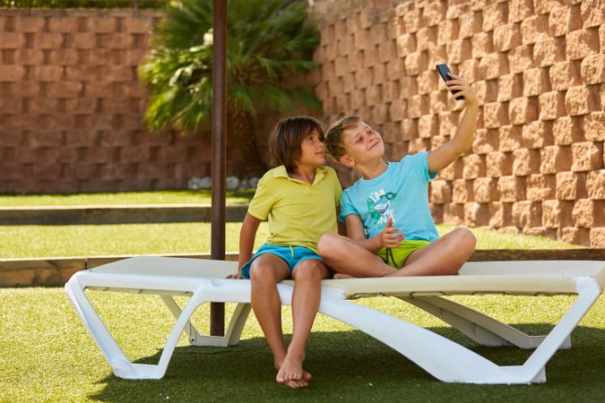 Cheerful boys taking selfie on sunbed