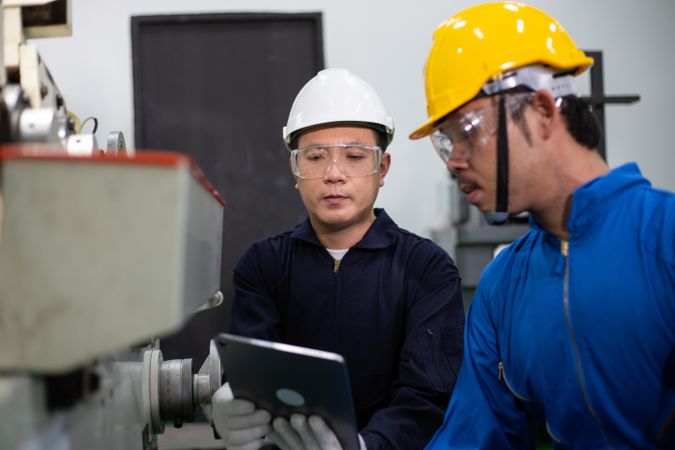 Two Asian males working together in factory