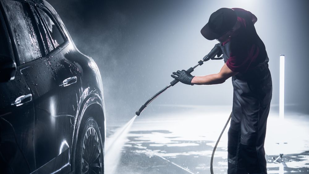Advertising Style Photo of a Professional Car Wash Specialist Using a High Pressure Washer to Clean and Prepare a  SUV