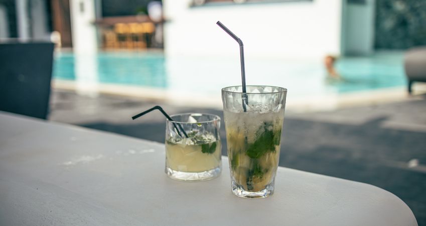 Two cocktails on a table with pool view behind
