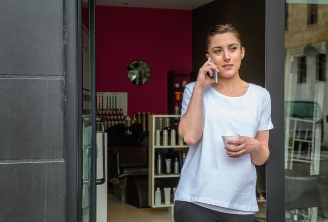 Female hairdresser taking call outside of salon during break