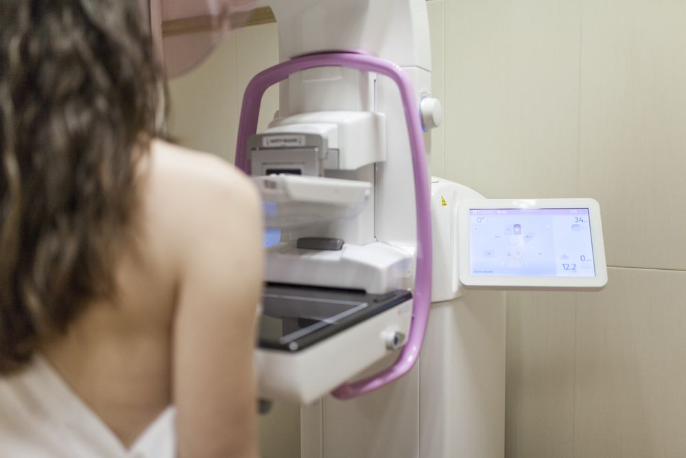 Female patient beside digital mammography unit