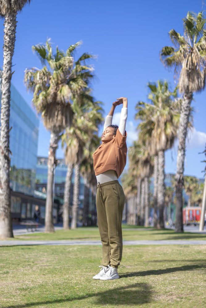 Black woman doing yoga under the palms in a promenade