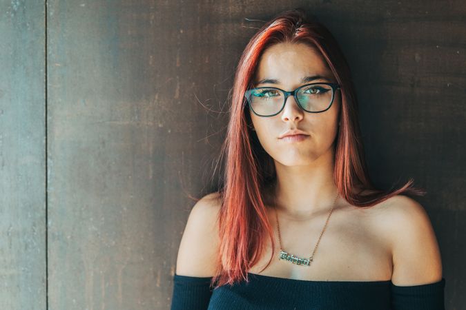 Woman in glasses leaning on wall