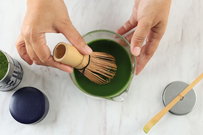 Woman Hand Whiskin Mathca using Chasen on Clear Bowl