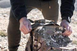 A young male is opening his military bag in the nature