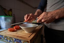 Anonymous man grating tomato into bowl