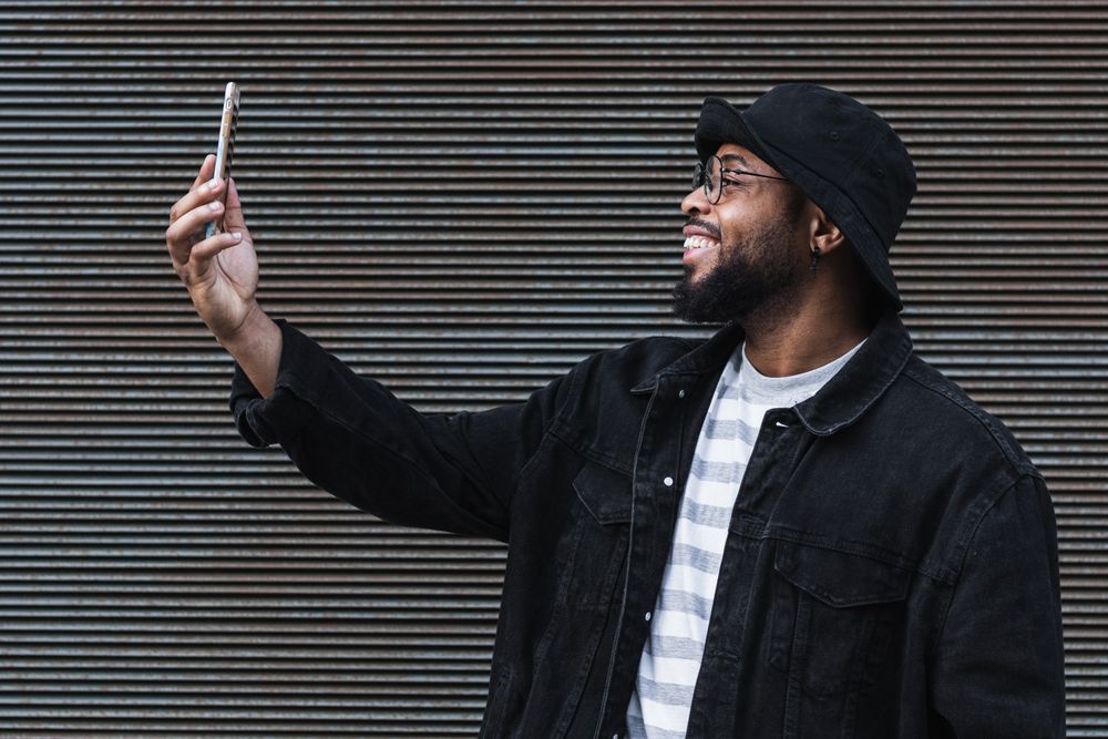 Laughing Black man taking selfie on smartphone