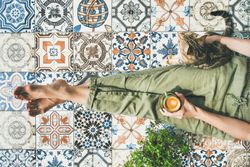 Woman on tiled terrace with coffee and cat