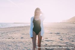Young woman standing on beach with sunset at her back 5RDJBb