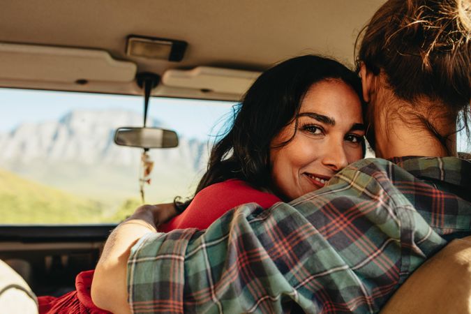Happy woman hugging her boyfriend while sitting in car together
